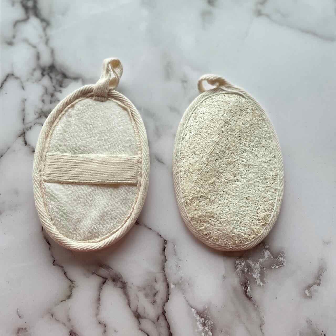 set of 2 loofah shower pads on top of a marble surface