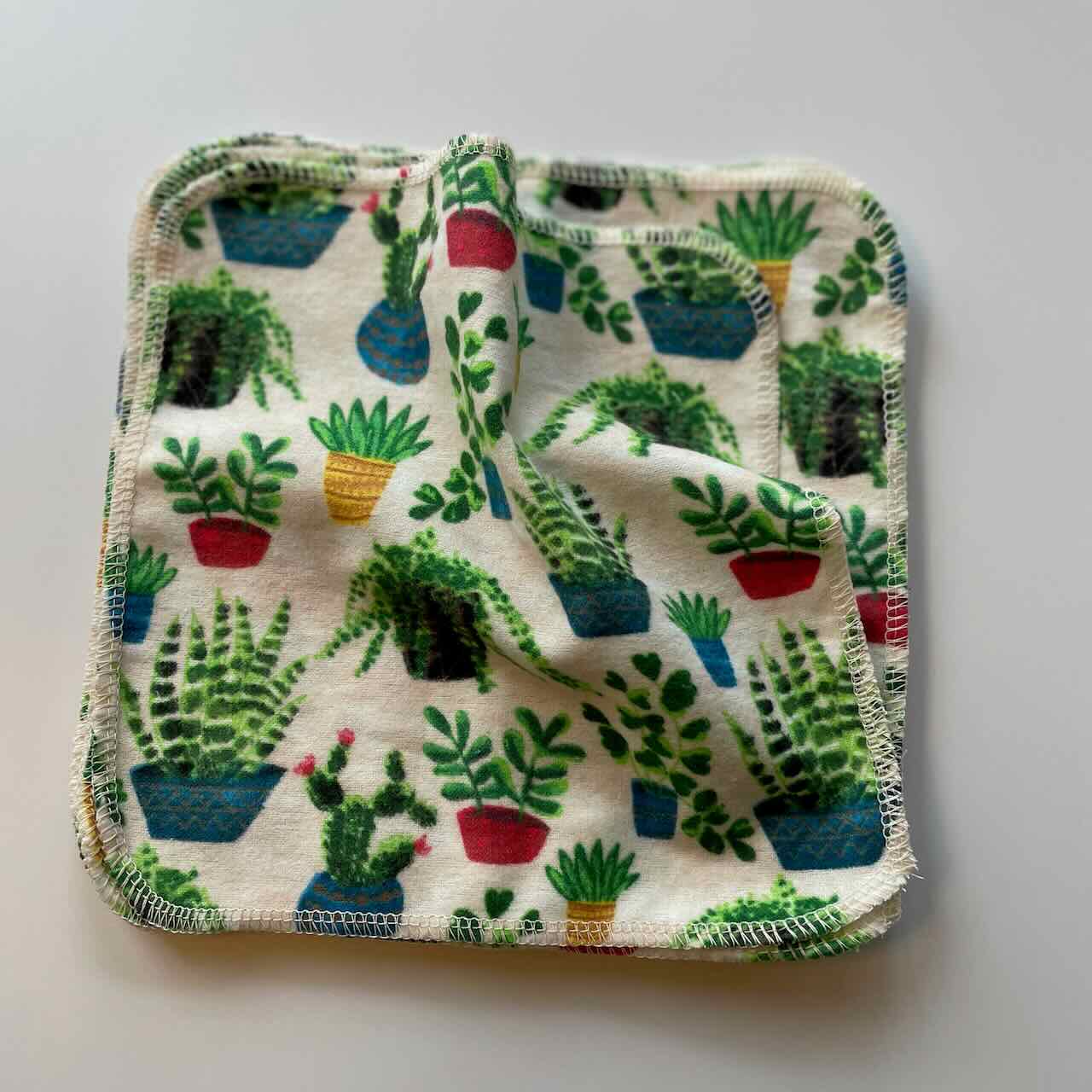 flatlay of a set of 10 reusable cloth wipes, with vibrant cactus plants printed on the fabric.