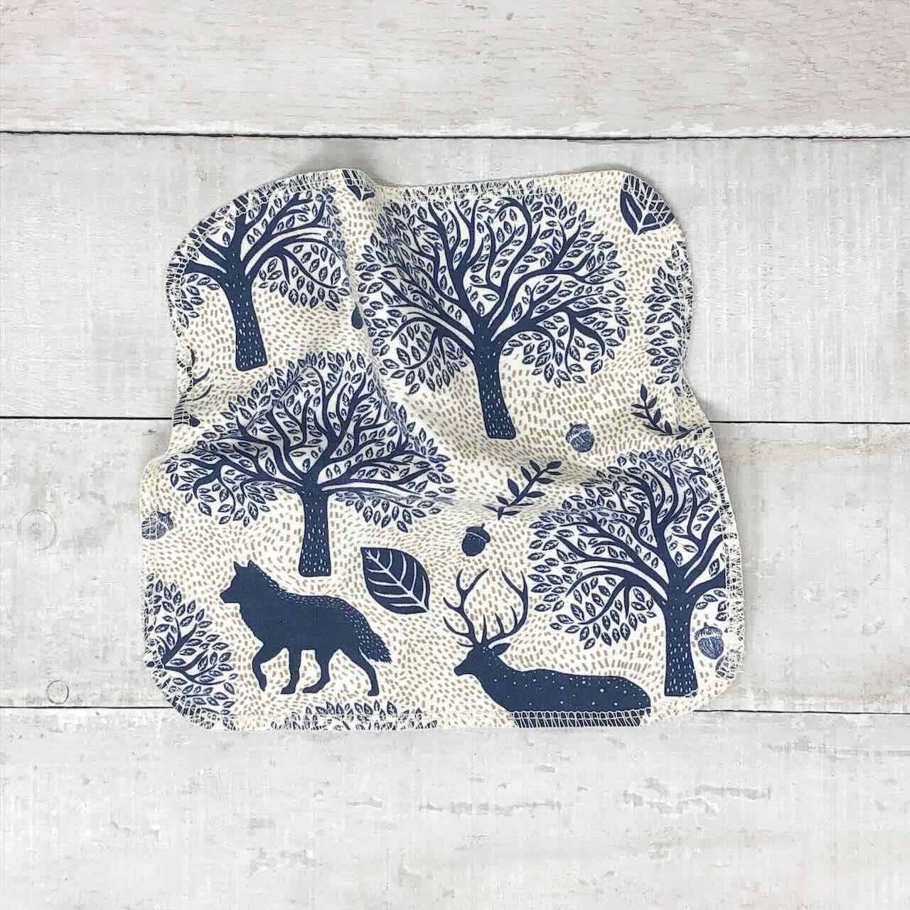 flat lay of a set of 10 reusable cloth wipes, with elegant forest animals printed on the fabric.