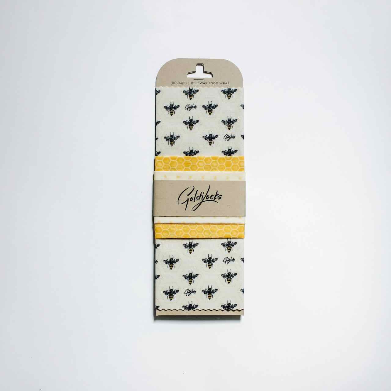 Goldilocks honey comb and bees themed beeswax wrap in its retail packaging, flatlay.