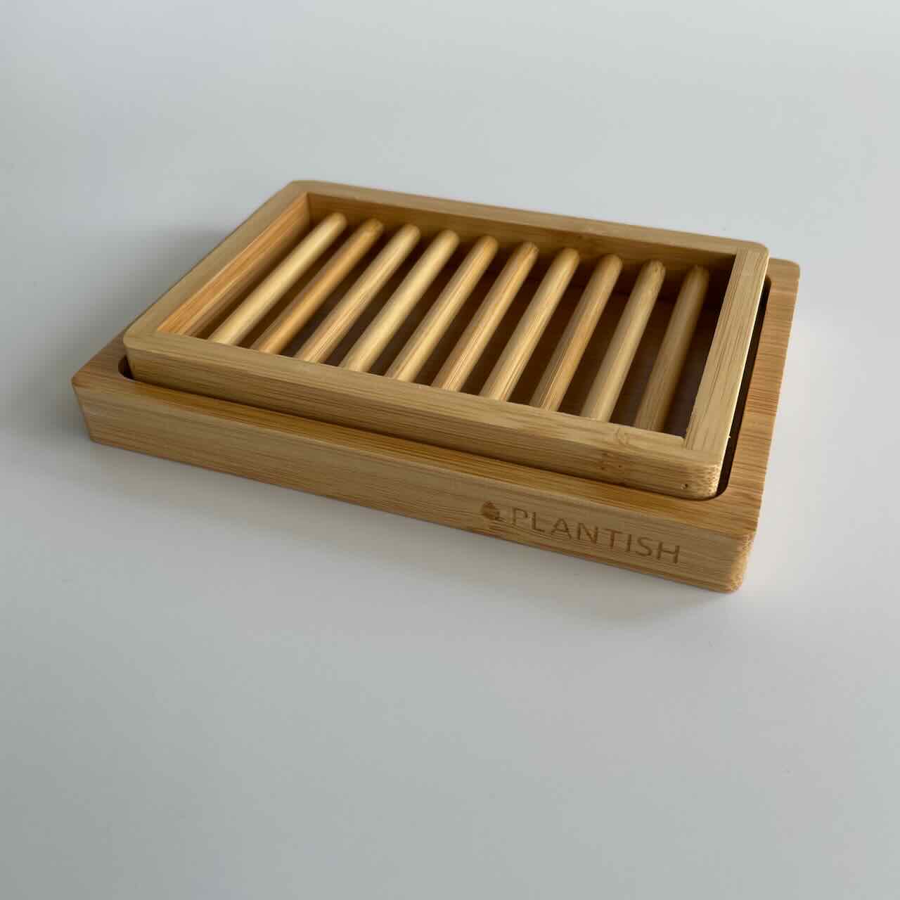 A bamboo two layered soap dish on a white table top.