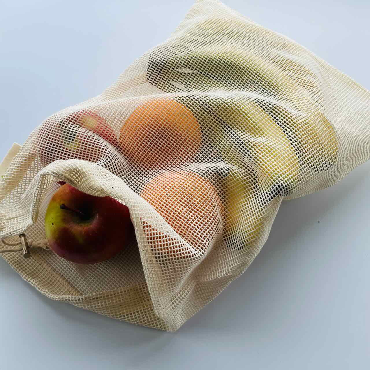 a large mesh bag containing bananas, oranges and apples