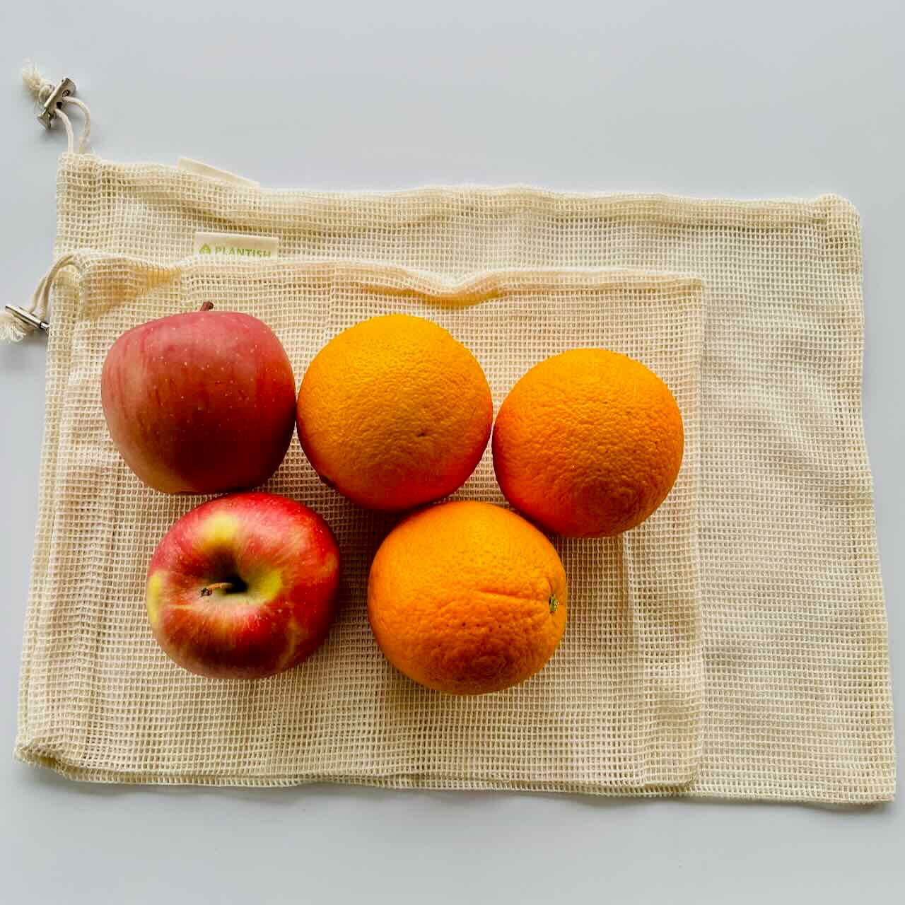 oranges and apples on top of mesh bags