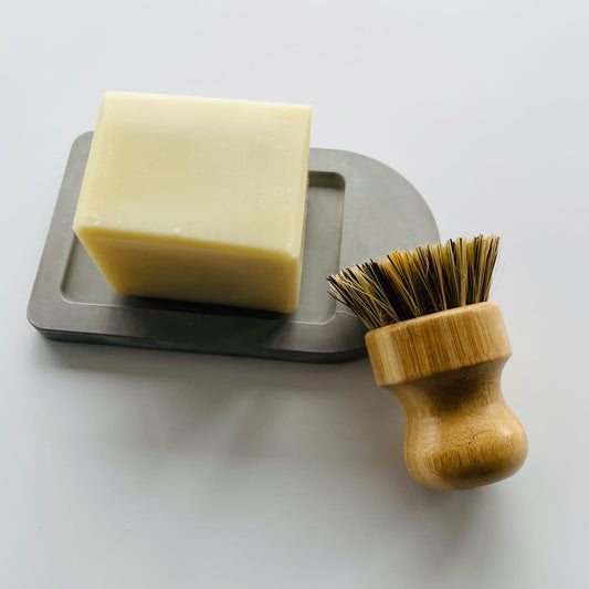 solid dish soap on a diatomite soap dish, with sisal scrubber leaning next to it