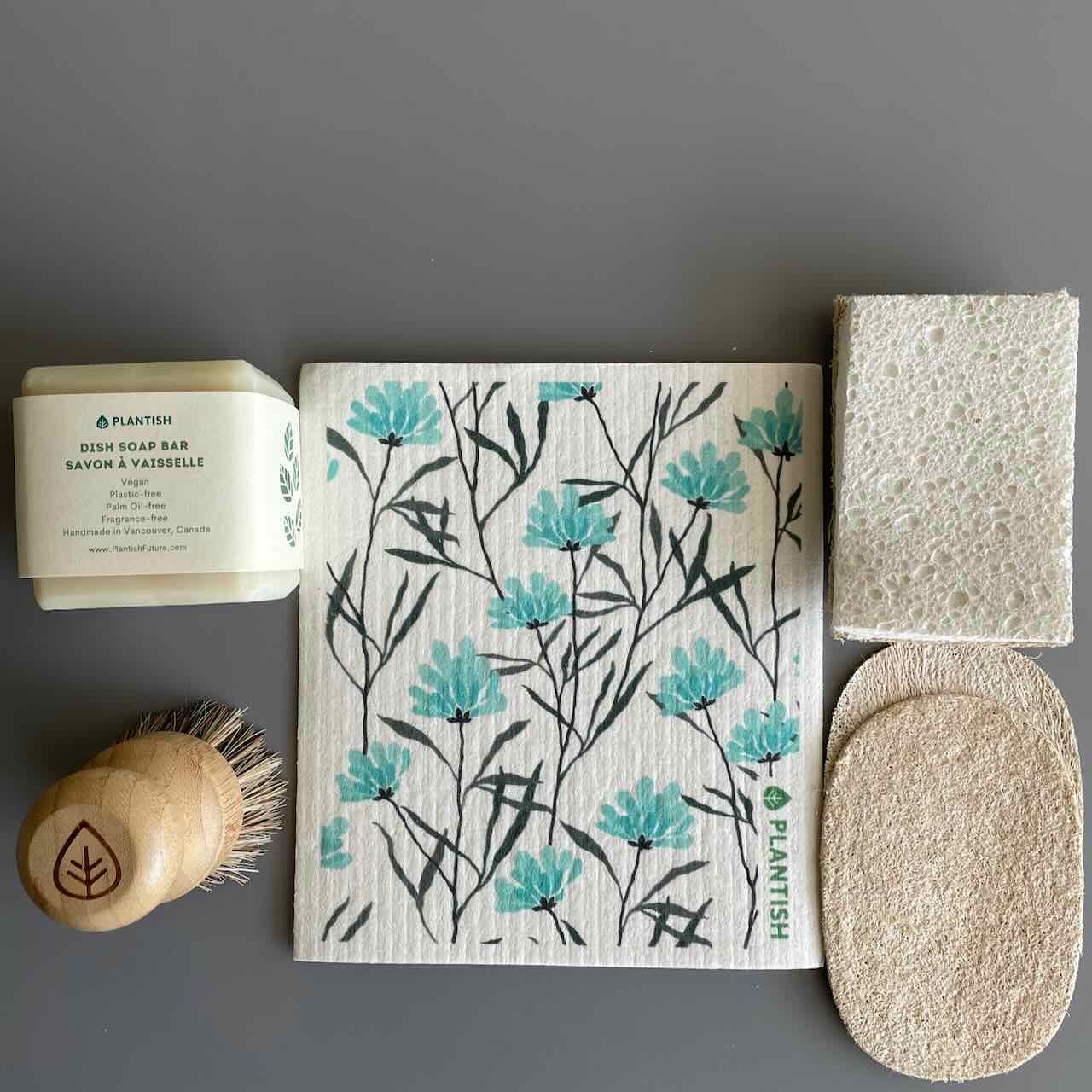 dish soap bar, sisal scrubber, eco sponges and swedish discloths laid on top of a grey table top